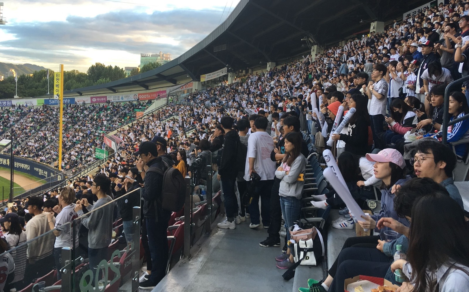 Les tribunes pleines du stade de Jamsil à Séoul, pendant un match de KBO au coucher du soleil.